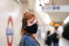 Woman wearing coronavirus face covering on London Underground platform 