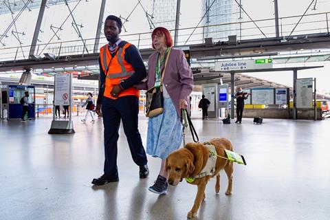 A member of staff helps a blind customer at Stratford London Underground station