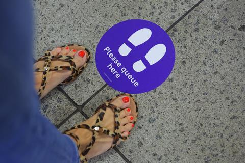 'Please queue here' station floor sign